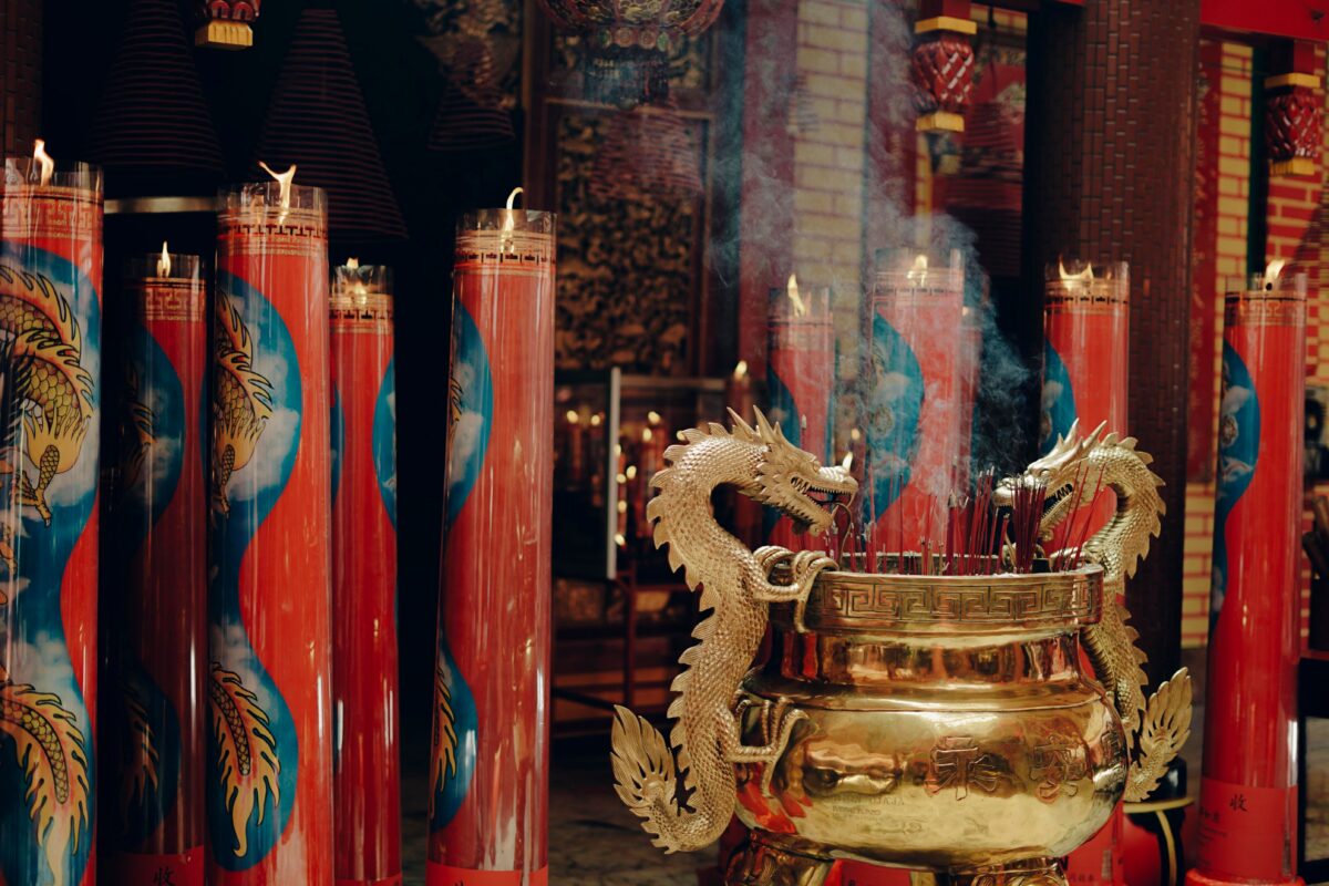 Golden dragon incense urn surrounded by large red candles in an Indonesian temple