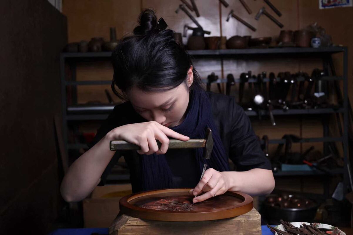 A female artisan is crafting pieces from silver