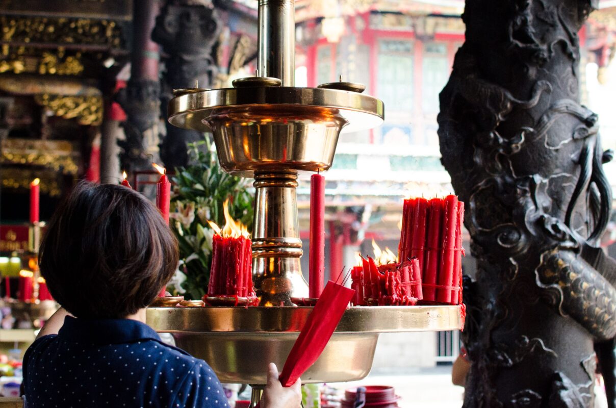 Woman lighting red candles in a Taiwanese temple
