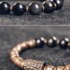 Close-up of glossy black obsidian beads and textured brass tube bead