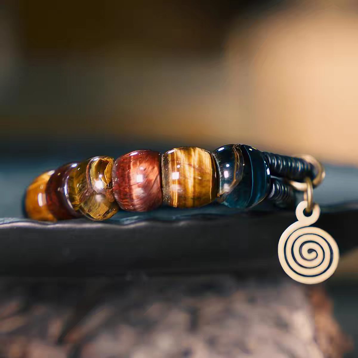 Close-up of multicolor tiger eye beads and brass spiral charm