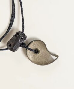 Close-up of gold sheen obsidian half-moon pendant, carved ebony top bead, and black braided cord