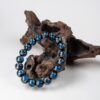 Blue Incense Ash Liuli Bead Bracelet — blue patterned bead bracelet propped against wood