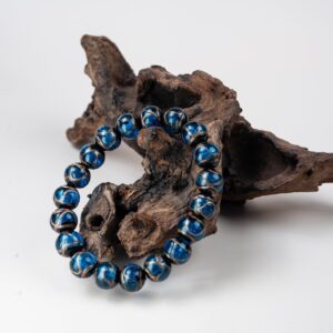 Blue Incense Ash Liuli Bead Bracelet — blue patterned bead bracelet propped against wood
