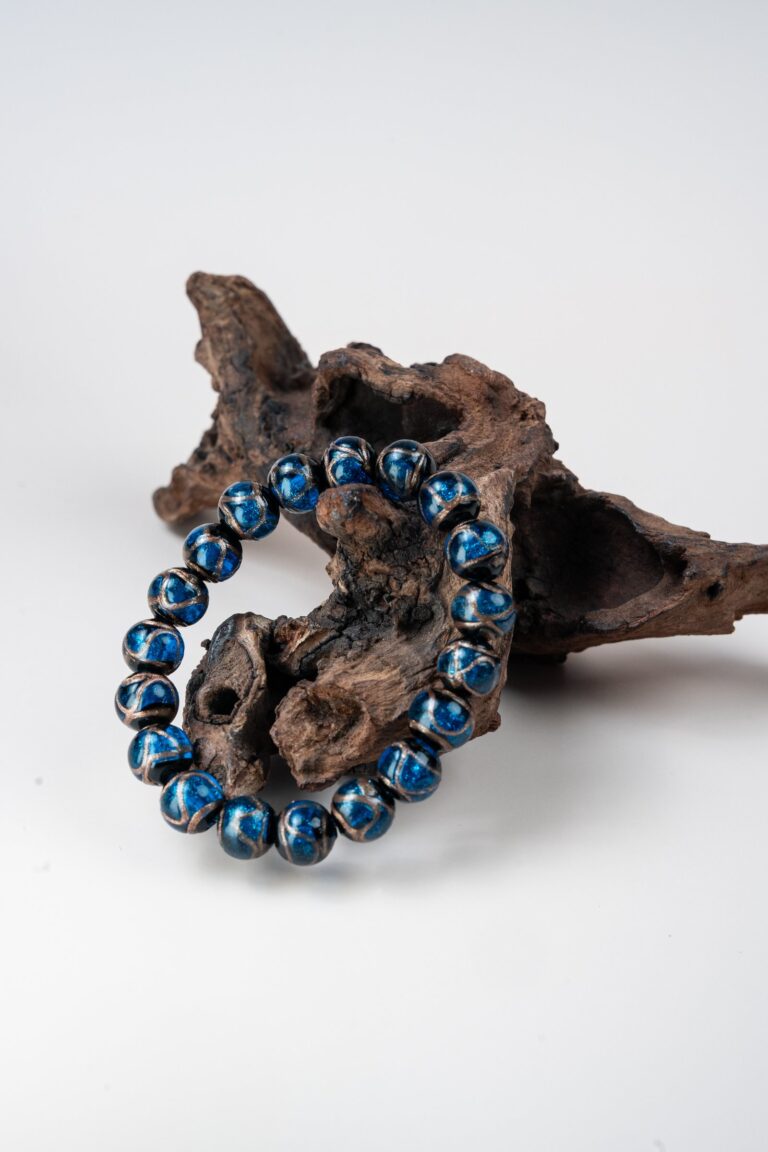 Blue Incense Ash Liuli Bead Bracelet — blue patterned bead bracelet propped against wood