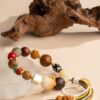 Bodhi Seed, Sandalwood & Dzi Bead Bracelet — multicolored bead bracelet with tassels beside wood