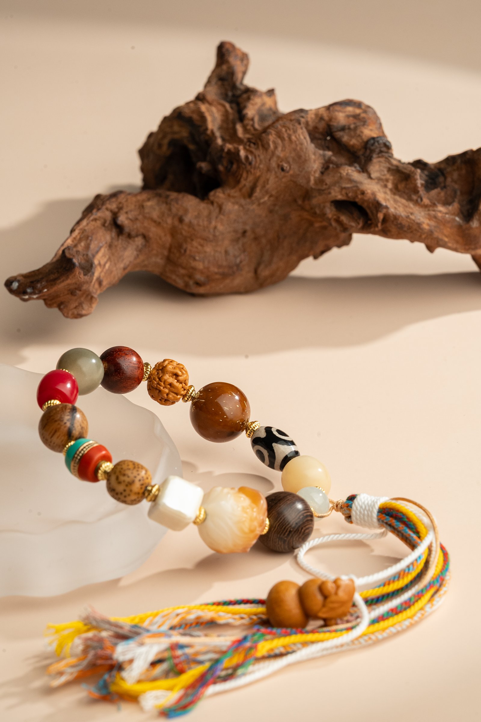 Bodhi Seed, Sandalwood & Dzi Bead Bracelet — multicolored bead bracelet with tassels beside wood