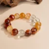 Chinese Zodiac Ox Bracelet — orange and red translucent bead bracelet beside wood