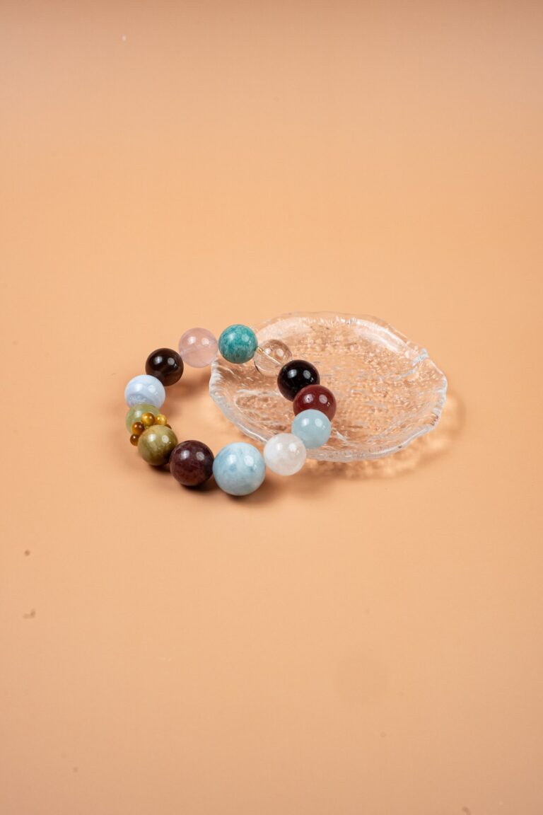 Earth Multi-Gemstone Aquamarine Golden Tiger Bracelet — multicolored translucent bead bracelet on a clear dish