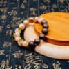 Eli Zhangzhong Fragrance Full Bracelet — brown and pale bead bracelet on a round wooden display