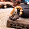 Eli Zhangzhong Fragrance Full Bracelet — brown and pale bead bracelet beside a dark teapot