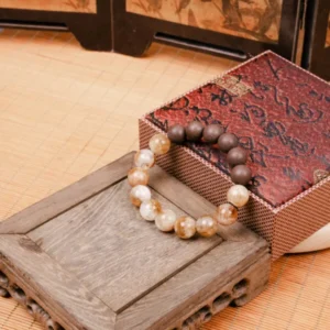 Eli Zhangzhong Fragrance Full Bracelet — brown and pale bead bracelet beside a patterned box