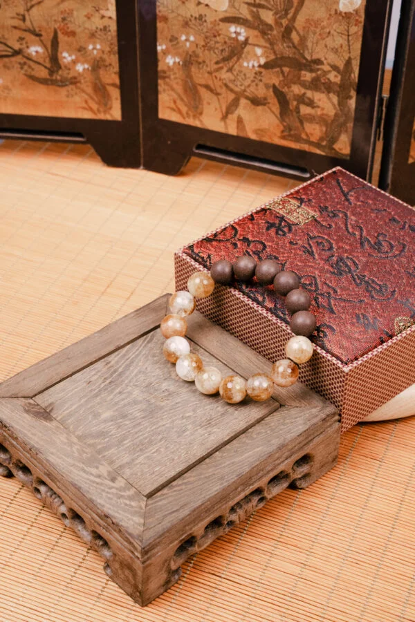 Eli Zhangzhong Fragrance Full Bracelet — brown and pale bead bracelet beside a patterned box