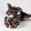 Five-Color Incense Ash Liuli Bead Bracelet — multicolored bead bracelet propped against wood