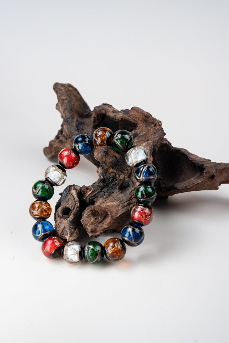 Five-Color Incense Ash Liuli Bead Bracelet — multicolored bead bracelet propped against wood
