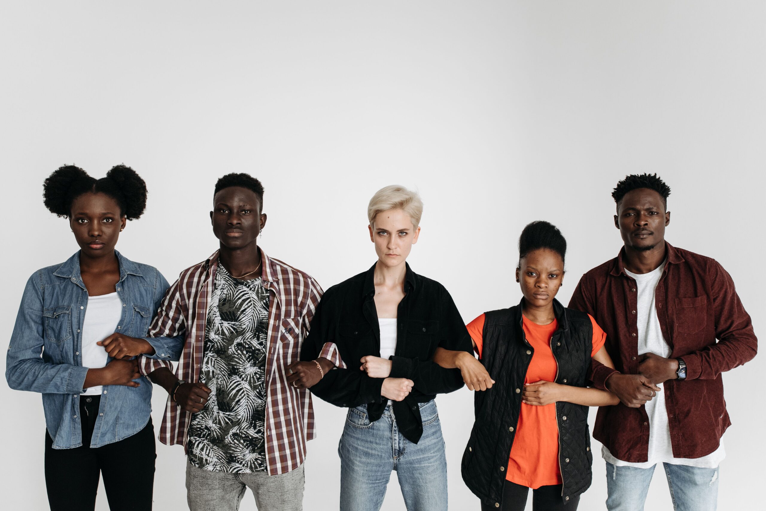 Five people standing together against a plain background