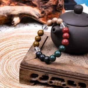 Five Elements Tianzi Herbal Incense Bracelet — multicolored bead bracelet beside a teapot