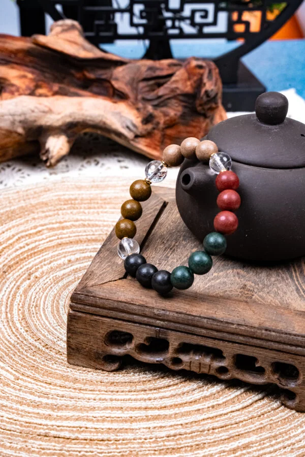 Five Elements Tianzi Herbal Incense Bracelet — multicolored bead bracelet beside a teapot