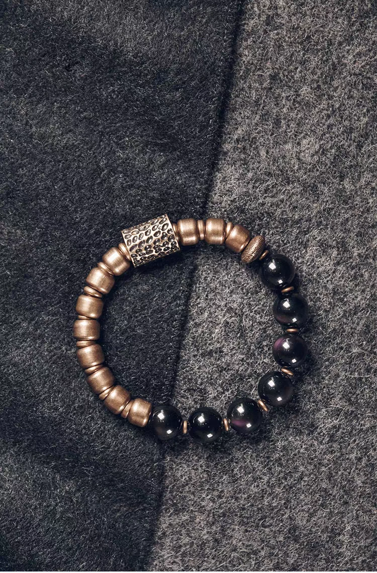 Fu Mo Xuan Tong bracelet with black beads and a textured metallic spacer on a dark surface