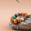 Fuling Agarwood & Bodhi Bead Bracelet — mixed-bead bracelet with tassels resting on a stone