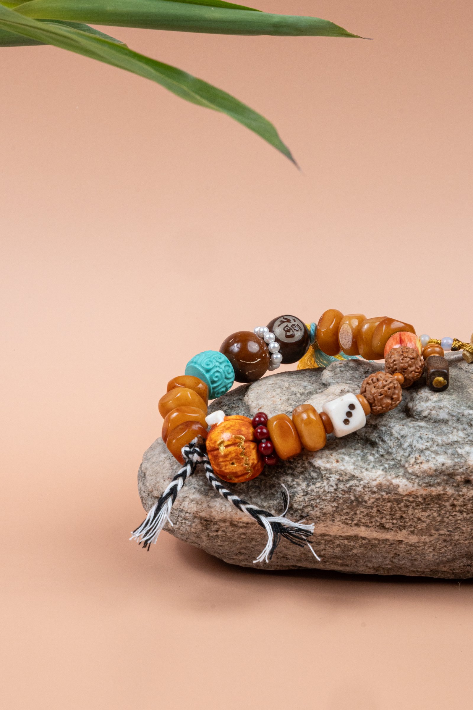 Fuling Agarwood & Bodhi Bead Bracelet — mixed-bead bracelet with tassels resting on a stone