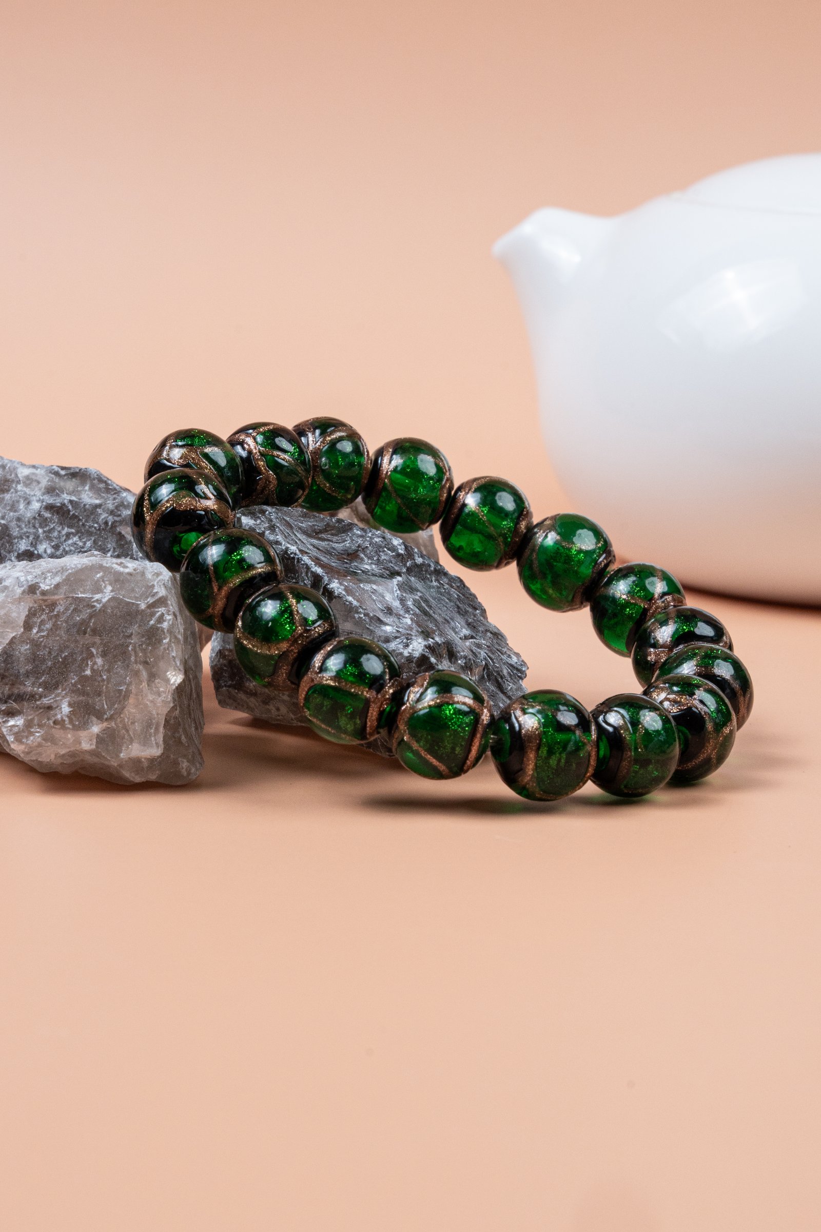 Green Incense Ash Liuli Bead Bracelet — green bead bracelet resting on stones beside a white vessel