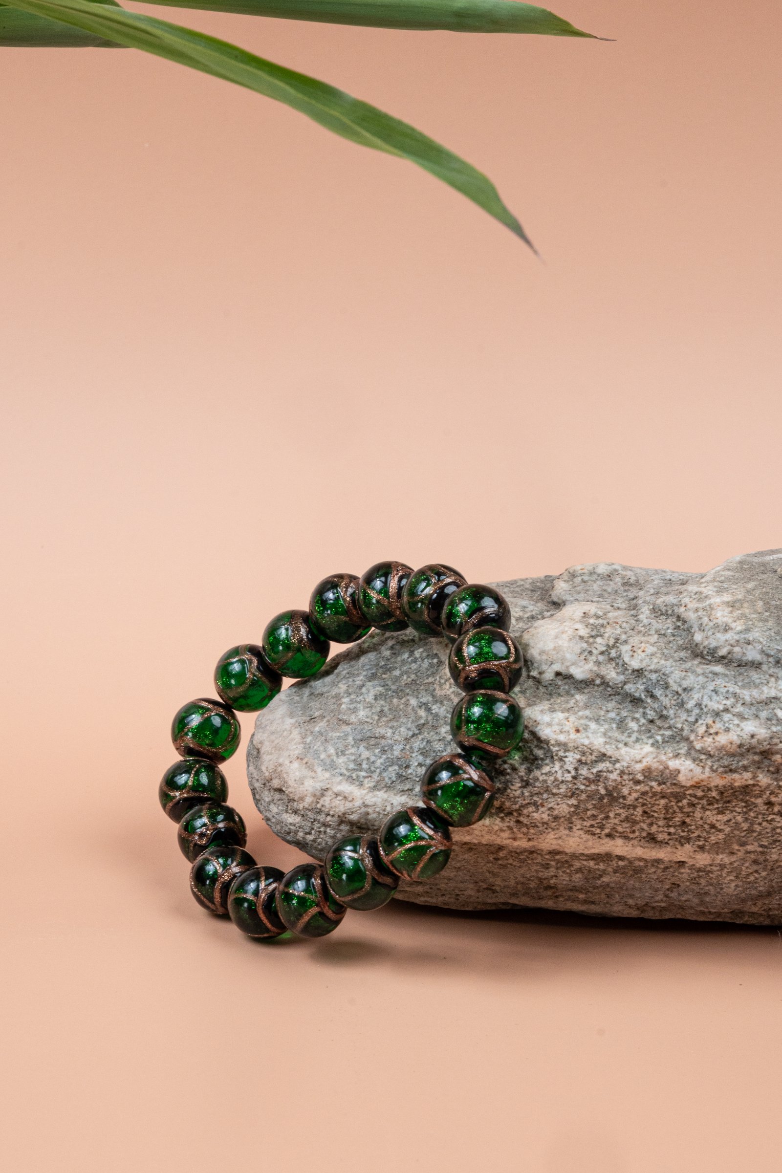 Green Incense Ash Liuli Bead Bracelet — green bead bracelet resting against a stone