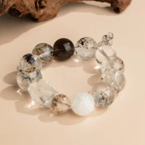 Ink-Wash Phantom Quartz Bracelet — translucent bead bracelet with dark inclusions beside wood