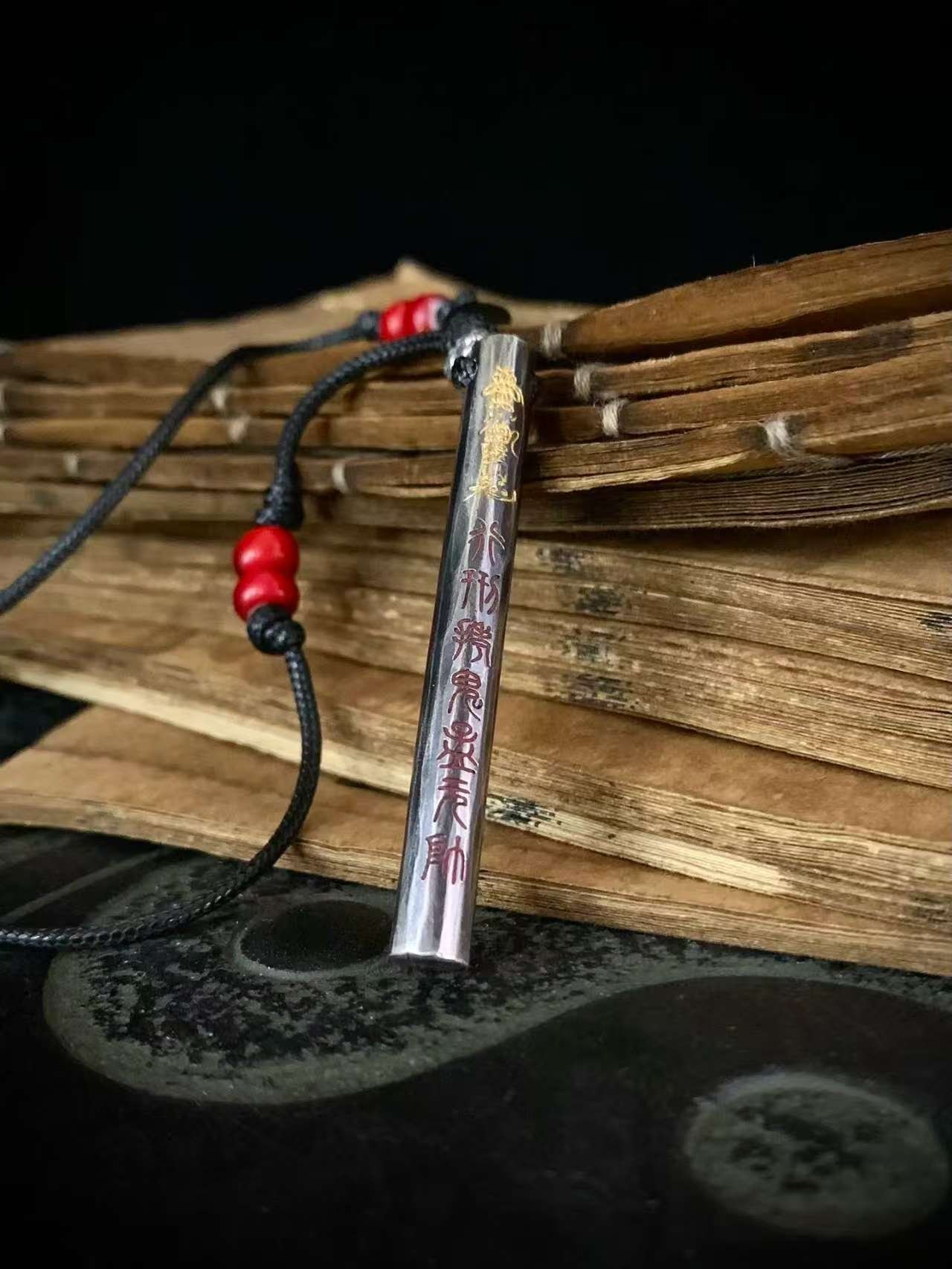 Kao Gui Rod 999 Silver Taoist Pendant — rod-shaped pendant resting against wooden slats