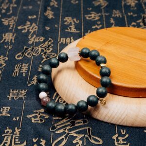 Meng Ling Xiang Herbal Incense Bracelet — dark green bead bracelet on a wooden display