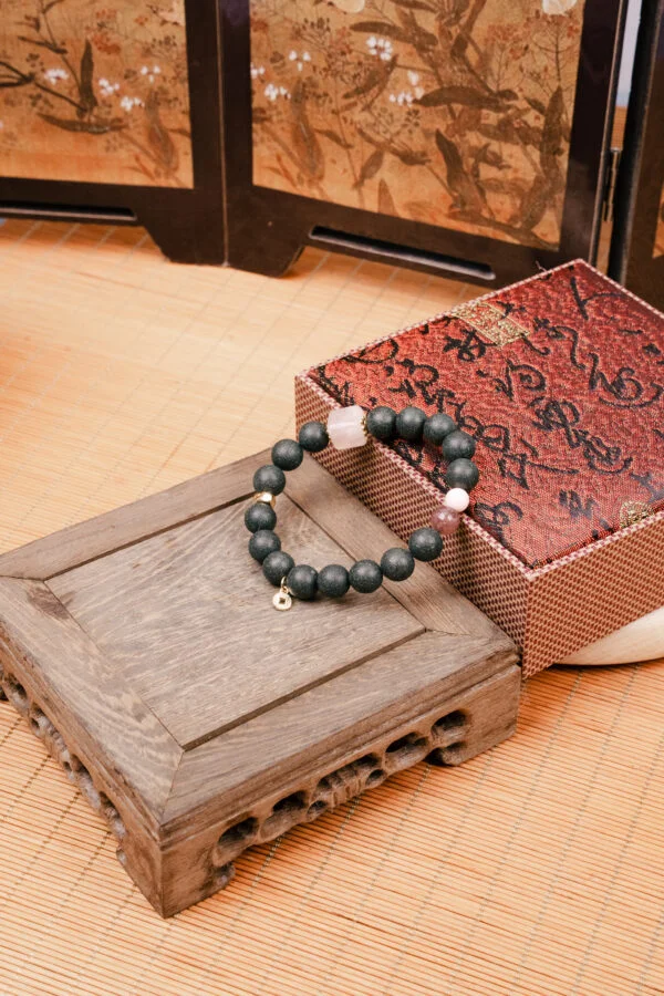Meng Ling Xiang Herbal Incense Bracelet — dark green bead bracelet beside a patterned box