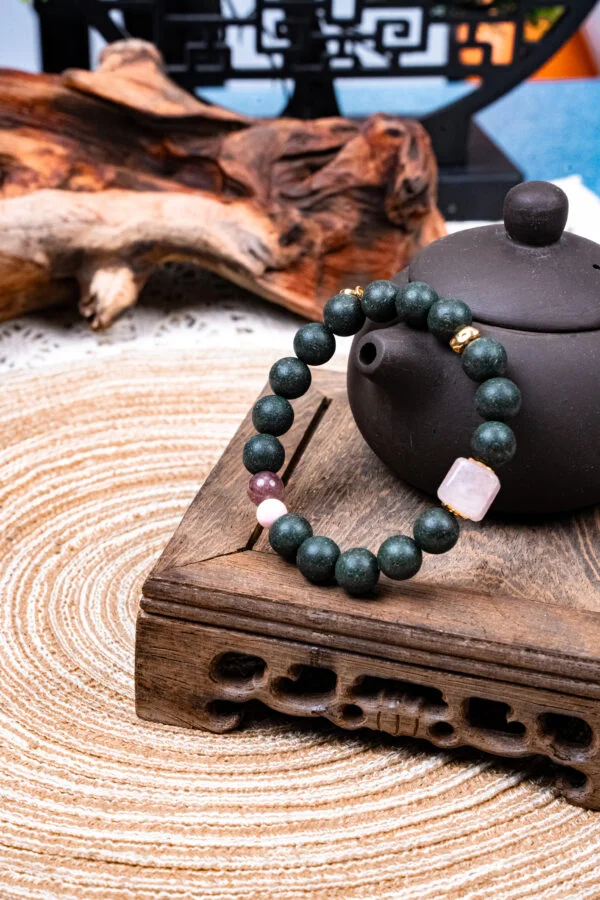 Meng Ling Xiang Herbal Incense Bracelet — dark green bead bracelet with pale accents beside a teapot