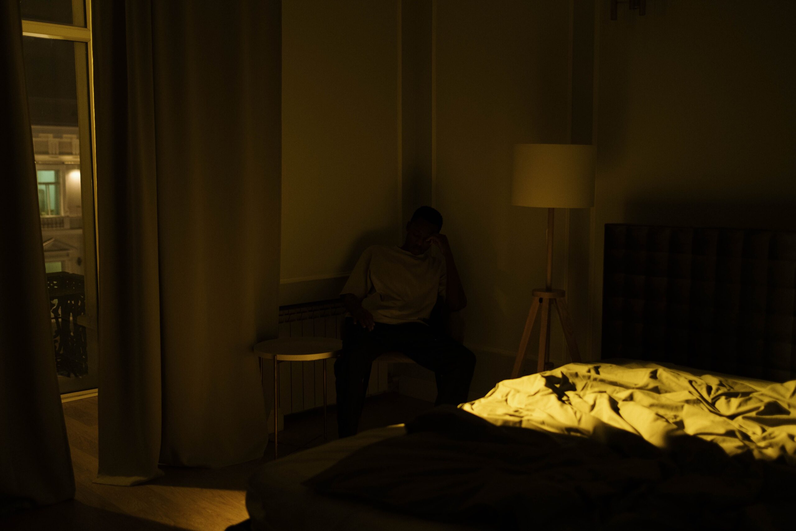 Person sitting in a dim bedroom