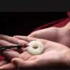 Pixiu Jade Pendant — pale carved circular pendant held in a palm