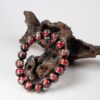 Red Incense Ash Liuli Bead Bracelet — red and black patterned bead bracelet propped against wood