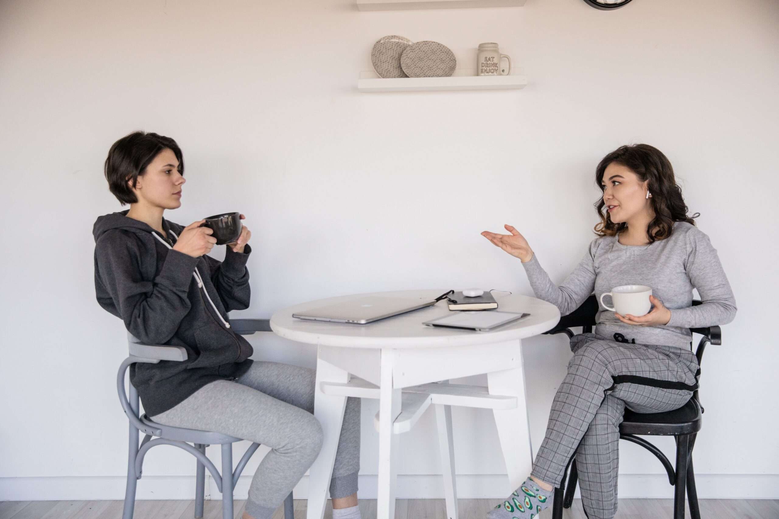 Two people talking over cups at a table