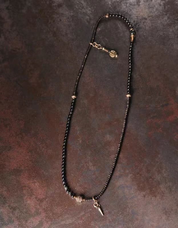 Vintage Floral Layered Obsidian Bracelet — long strand of dark beads with charms laid out on a textured surface