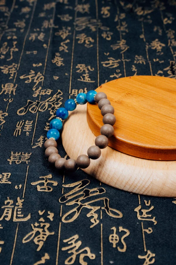 Wuzhen Herbal Incense Bracelet — brown and bright blue bead bracelet on a wooden display