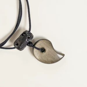 Close-up of gold sheen obsidian half-moon pendant, carved ebony top bead, and black braided cord