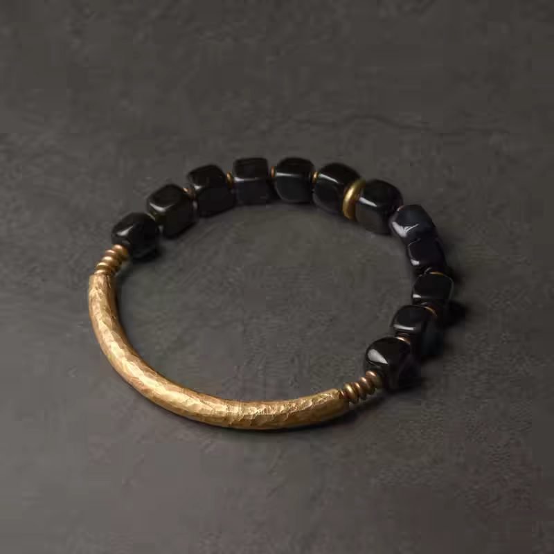 Xuan Ying Obsidian Bracelet — dark rectangular-bead bracelet with a curved gold-colored connector