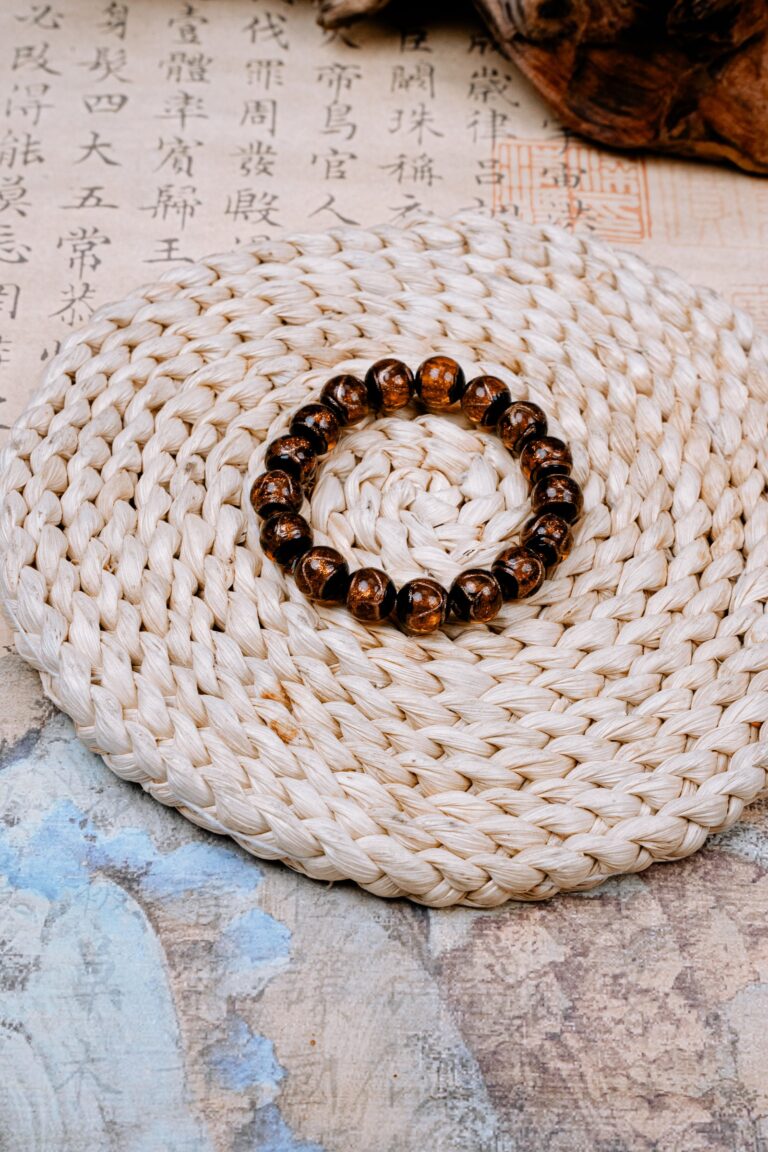 Yellow Incense Ash Liuli Bead Bracelet — bracelet with dark amber patterned beads on a woven mat