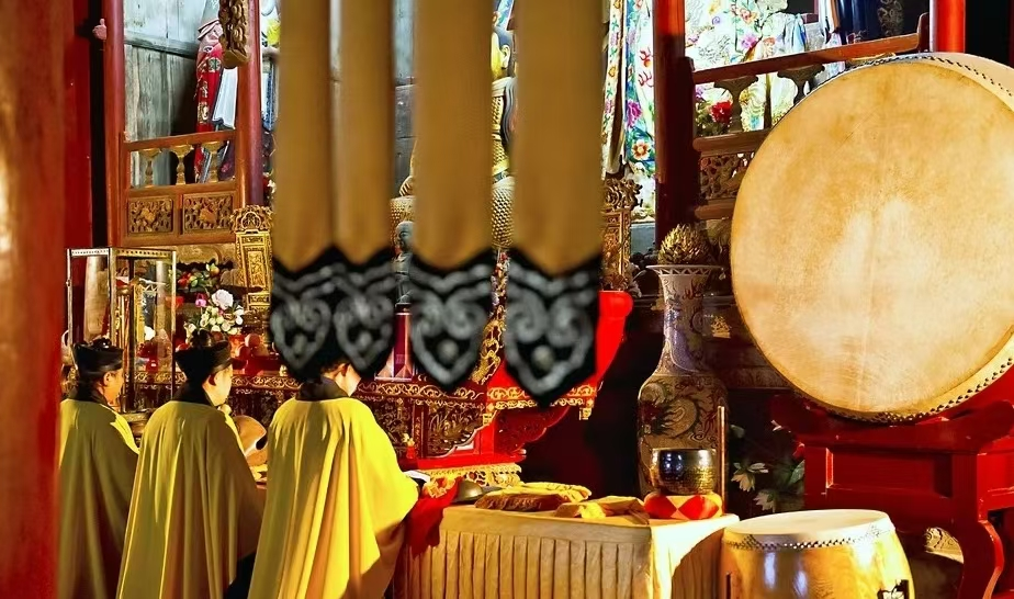 Yellow-robed practitioners at an altar beside drums