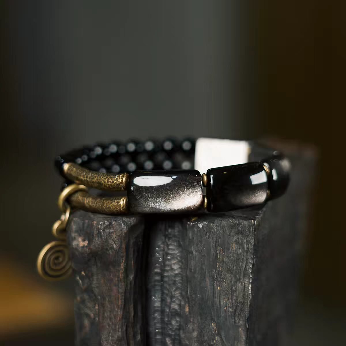 Yue Hua (Moonlight) Bracelet — dark bead and rectangular-link bracelet on a wooden support