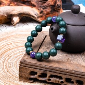 Zhizi Hexiang Herbal Incense Bracelet — dark green bead bracelet beside a teapot