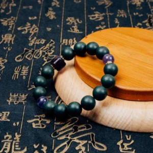 Zhizi Hexiang Herbal Incense Bracelet — dark green bead bracelet with purple accents on a wooden display