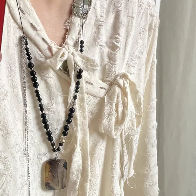 Zi Wei Ling Pendant — long dark bead necklace with a rectangular pendant worn over light clothing
